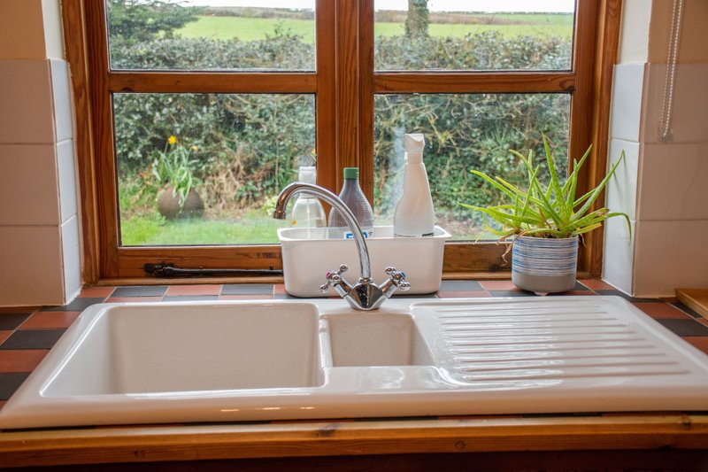 Kitchen sink with dual basins, chrome faucet, window overlooking rural countryside and fields