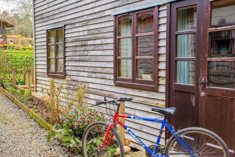 Exterior cottage wall with windows, doors, and two bicycles leaned against siding
