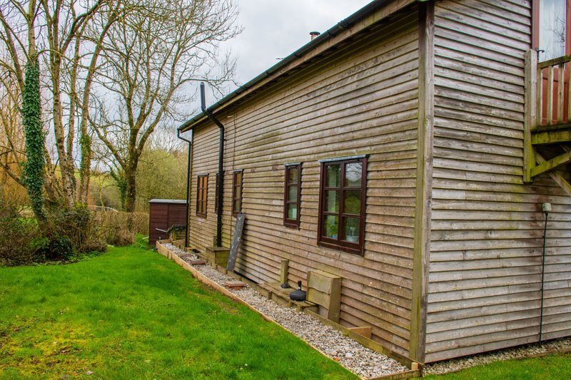 Modern wooden chalet exterior with green lawn, gravel path and bare trees