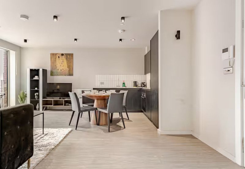 Open-plan kitchen and dining area with wooden table, modern cabinetry, and light wood flooring
