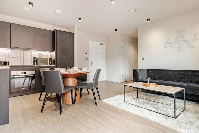 Open-plan living space with kitchen, dining table and seating area, wooden flooring
