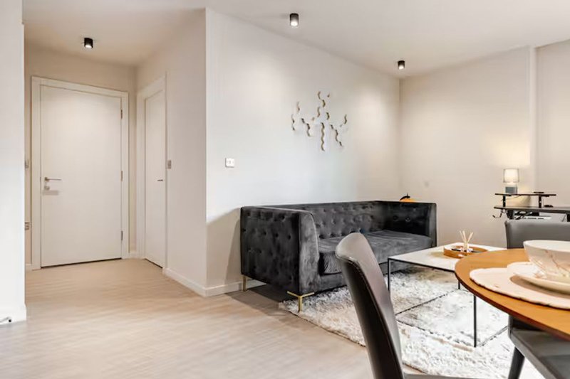 Open-plan living and dining area with dark sofa, wooden table, and modern decor