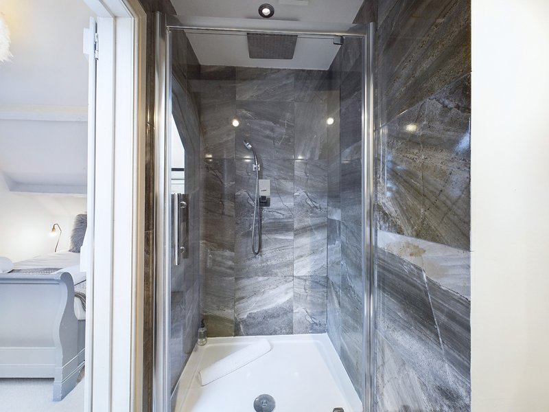 Modern bathroom with gray tiled walk-in shower enclosure and white bathtub