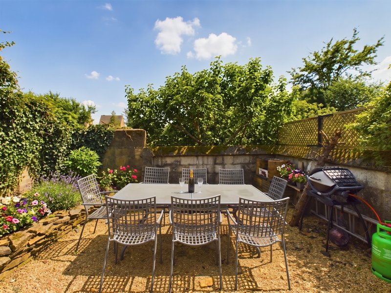 Outdoor patio area with dining table, chairs, flowering plants and climbing ivy