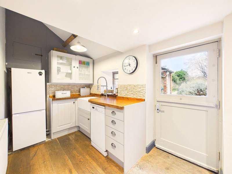 Modern kitchen with white cabinetry, yellow countertop, stainless steel appliances and garden view