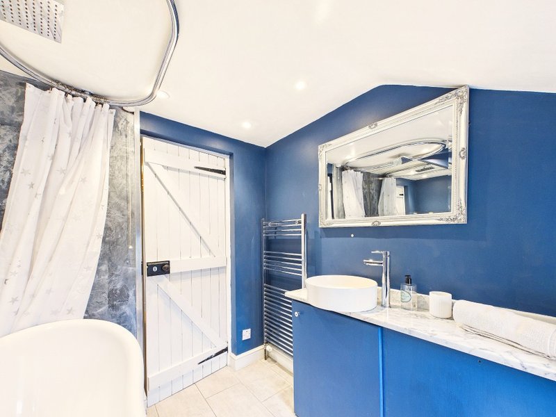 Modern bathroom with blue walls, white sink, mirror, towel rail and shower cubicle