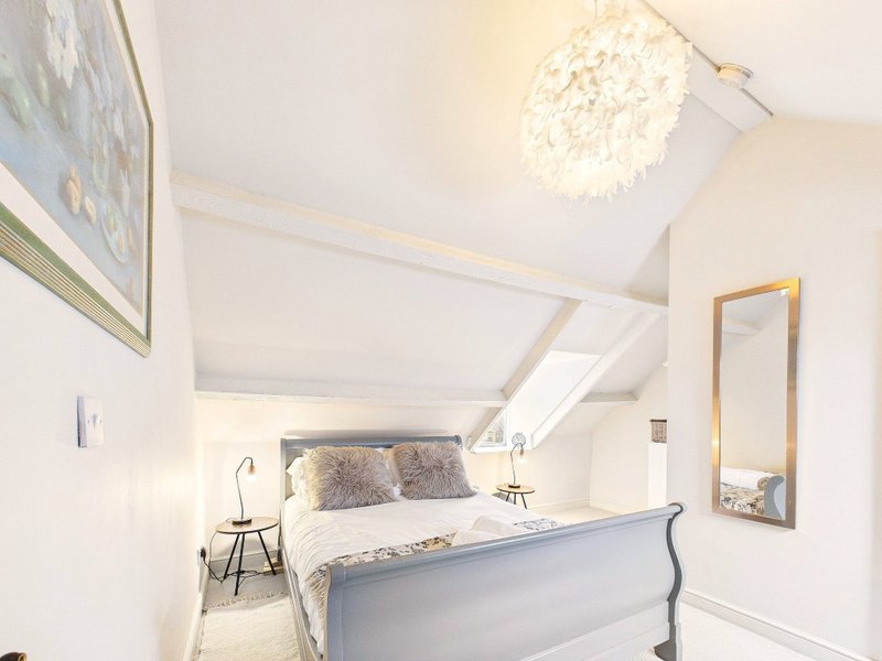 Bright attic bedroom with double bed, sloped ceiling, skylight window and mirror