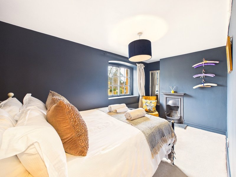 Modern bedroom with double bed, blue walls, pendant lamp and window view