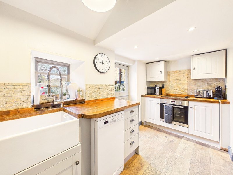 Modern kitchen with white cabinetry, wooden countertops, island, and brick backsplash