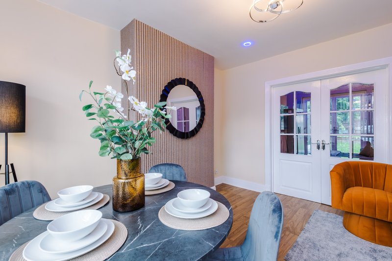 Modern dining room with set table, floral centerpiece, and orange velvet chair