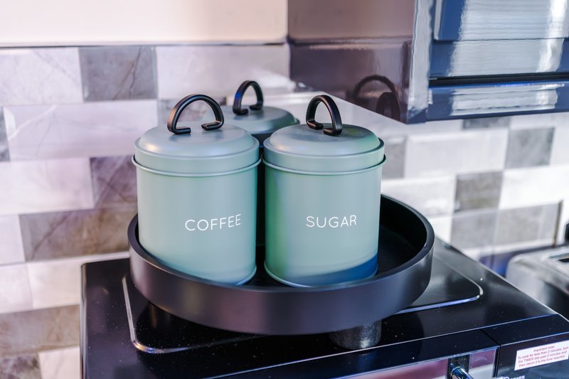 Kitchen counter with labeled coffee and sugar canisters, backsplash tiles visible