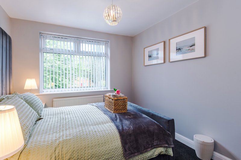 Bedroom with single bed, pendant light, window with blinds, and framed wall art