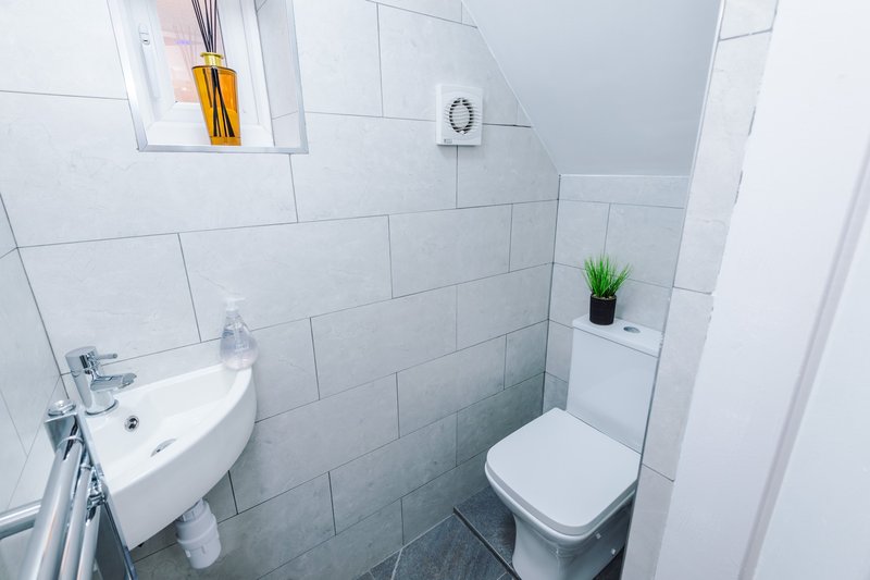 Modern bathroom with white subway tiles, wall-mounted sink, toilet, and small potted plant