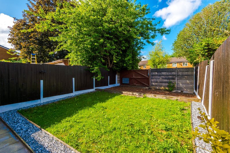 Spacious garden with manicured lawn, wooden fences, blue-painted posts and mature trees overhead