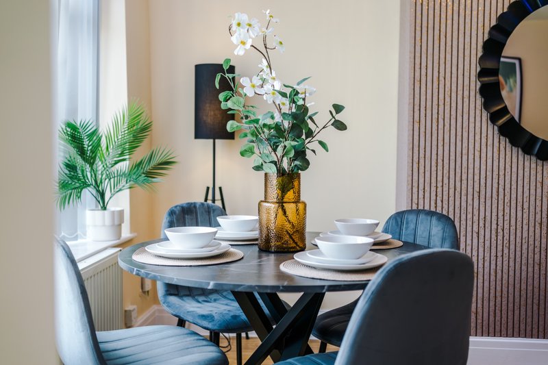 Dining room with round table, blue chairs, place settings, and floral centerpiece