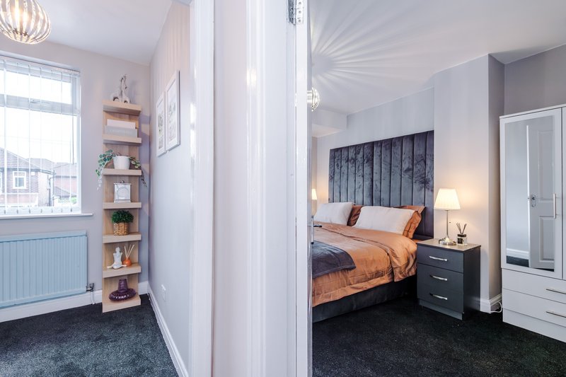 Modern bedroom with double bed, black headboard, orange bedding, and adjoining ensuite entrance