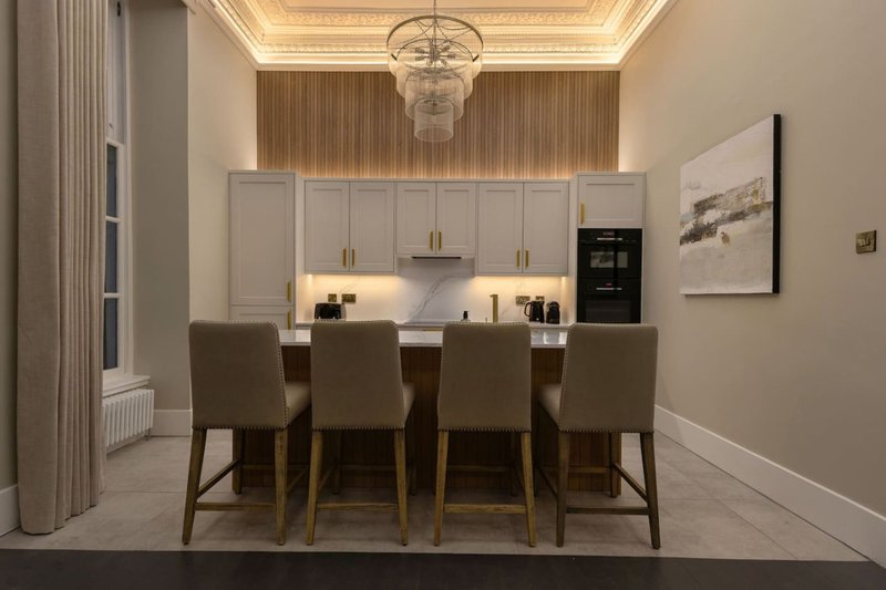 Modern kitchen and dining area with white cabinetry, island seating, and four upholstered chairs