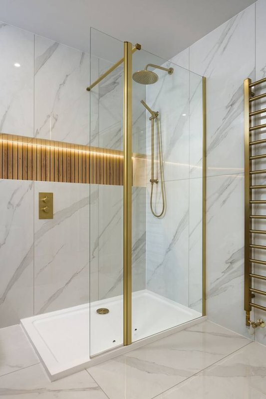 Modern bathroom with walk-in shower enclosure, marble tiles, brass fixtures and heated towel rail