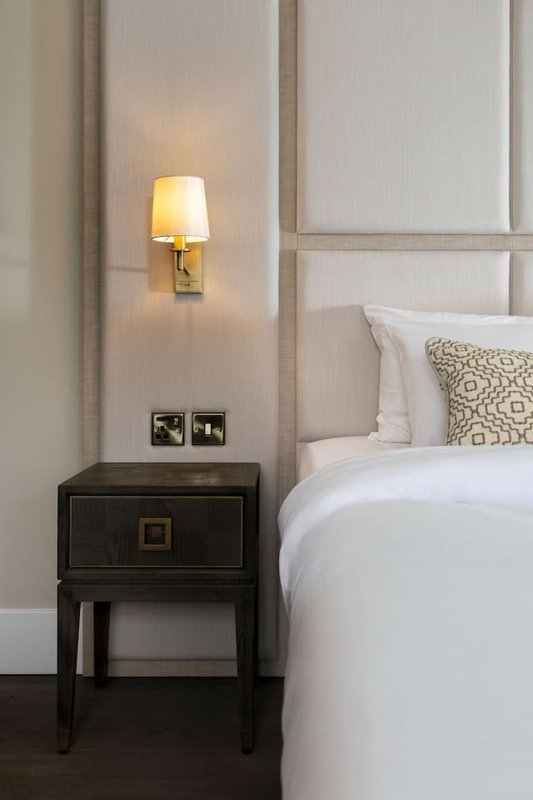 Modern bedroom with upholstered headboard, double bed, black nightstand and wall sconce