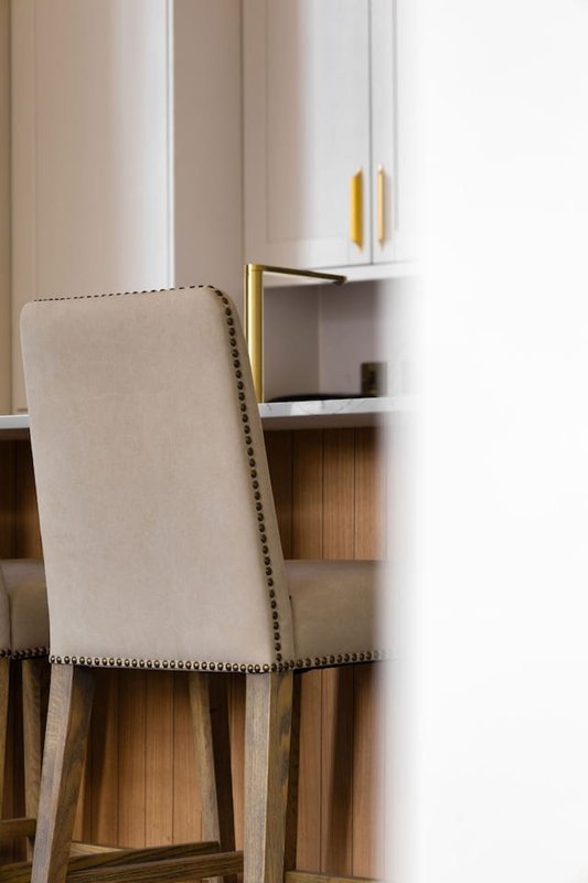 Upholstered dining chair with nailhead trim beside built-in shelving unit