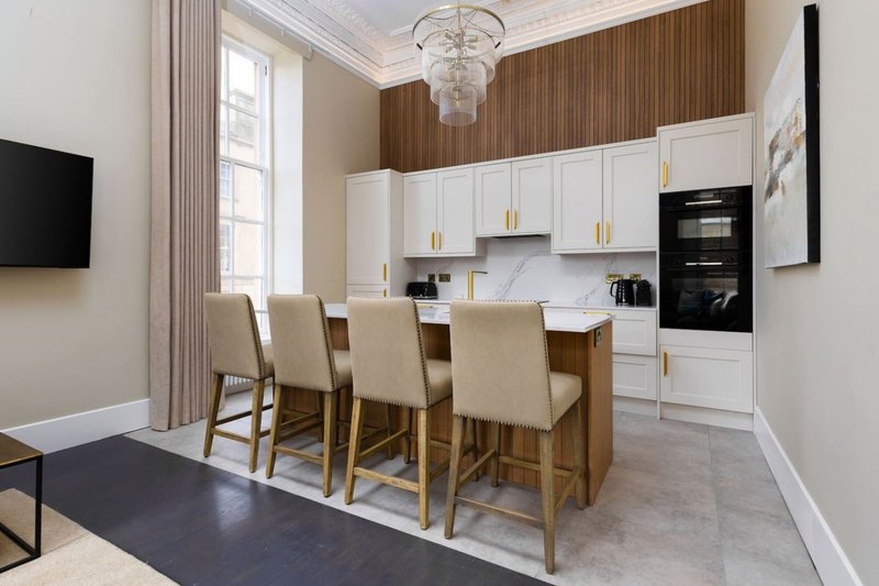 Modern open-plan kitchen and dining area with white cabinetry, wooden accents, and dining table for four