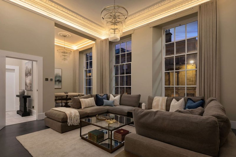 Spacious living room with sectional sofa, large windows, chandelier and fireplace