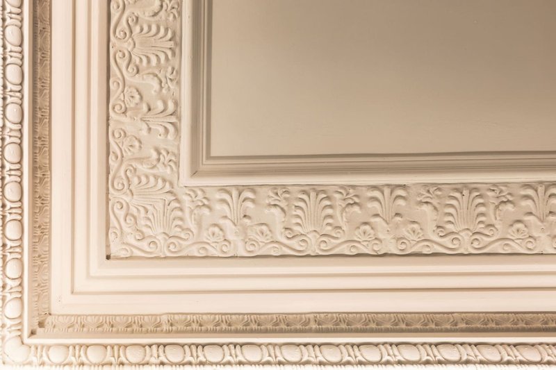 Ornate cream-colored decorative ceiling cornice and wall paneling with classical molding details