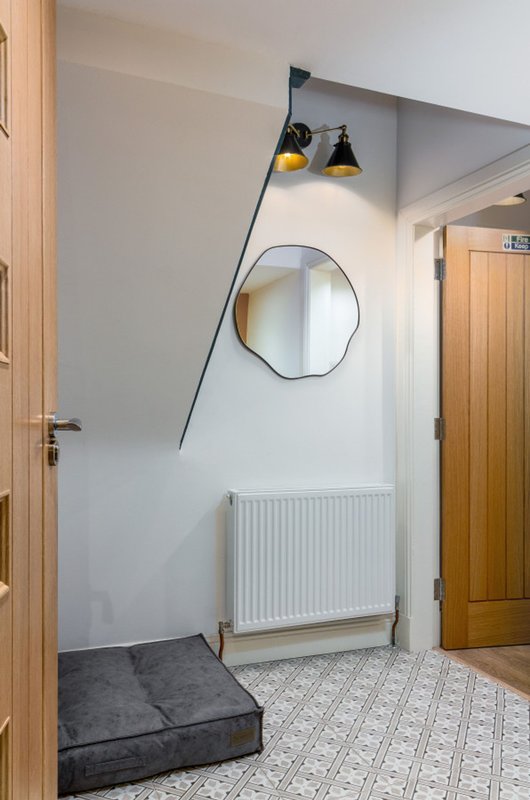 Hallway with round mirror, pendant lights, radiator and black floor cushion