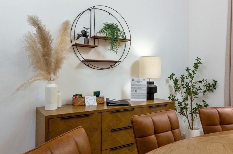 Modern dining area with wooden sideboard, leather chairs, decorative wall shelf and plants
