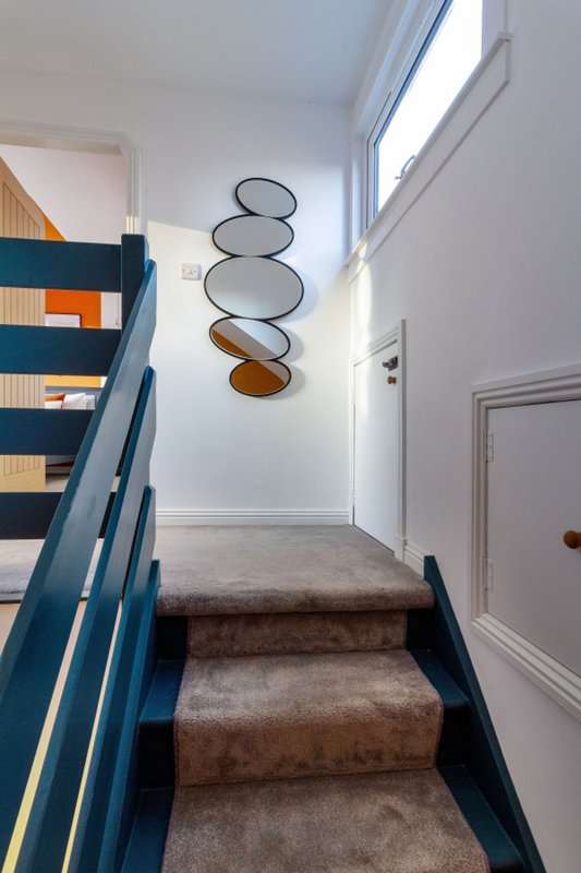 Stairwell with blue railings, carpet treads, and decorative hanging plates