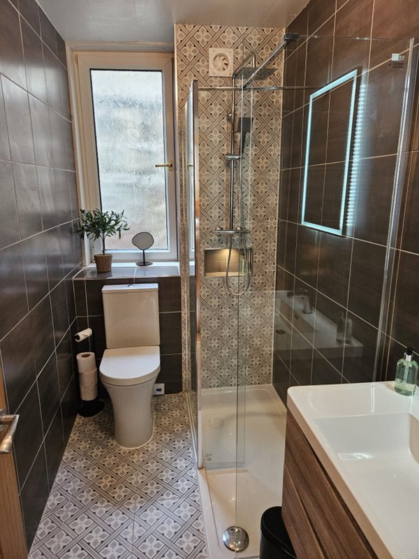 Modern bathroom with walk-in shower, toilet, vanity sink and window with winter view