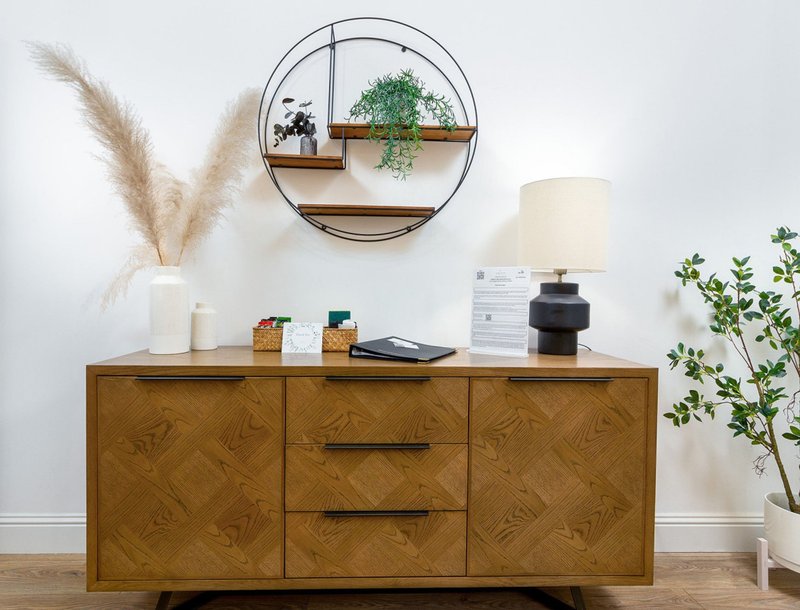 Modern wooden sideboard with decorative items, wall art, pampas grass and potted plants