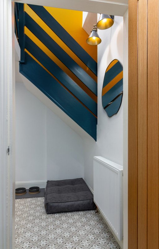 Narrow entryway with geometric wall art, pendant lights, and patterned floor tiles