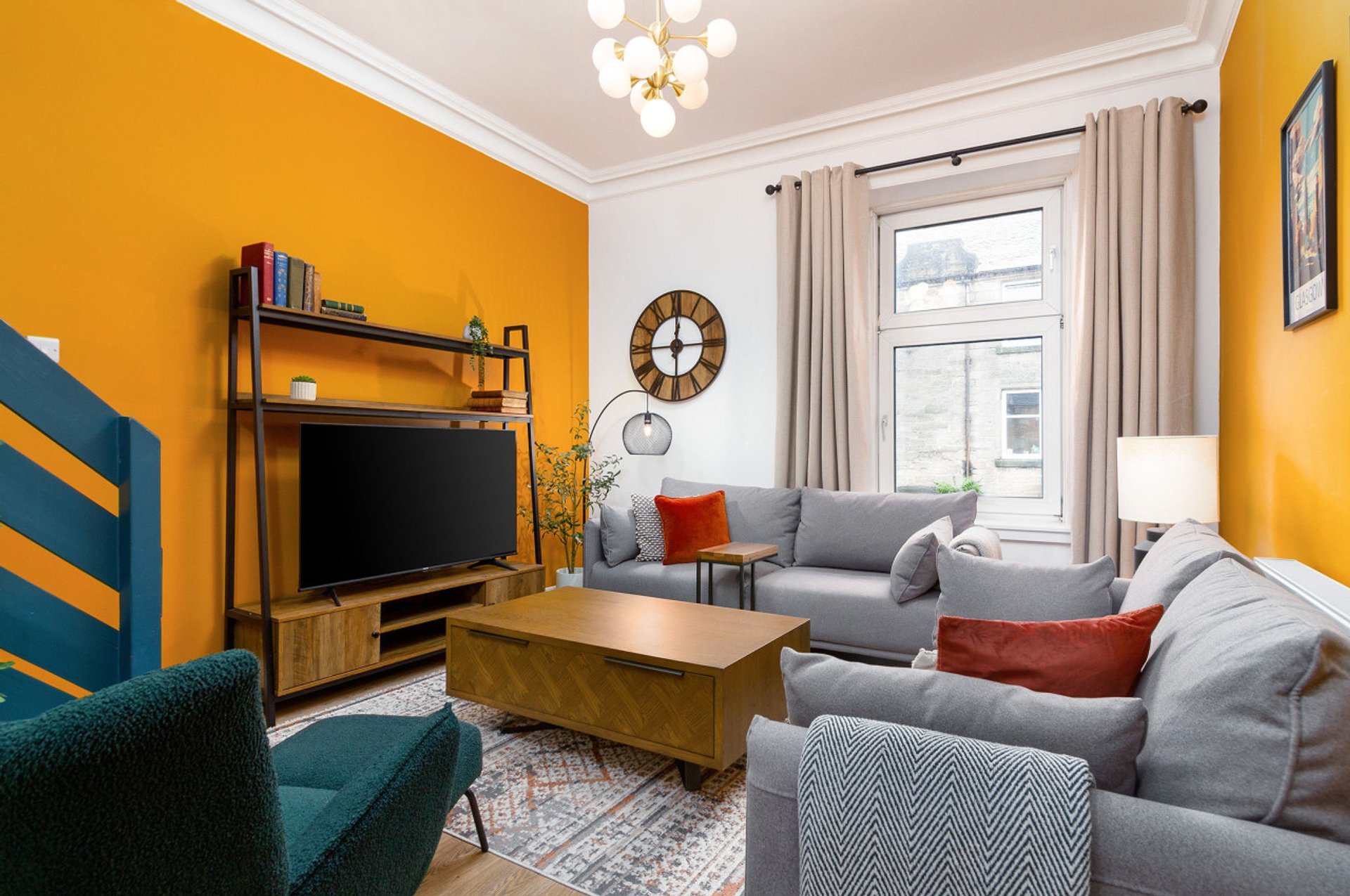 Bright living room with orange walls, gray sofa, wooden coffee table and TV unit