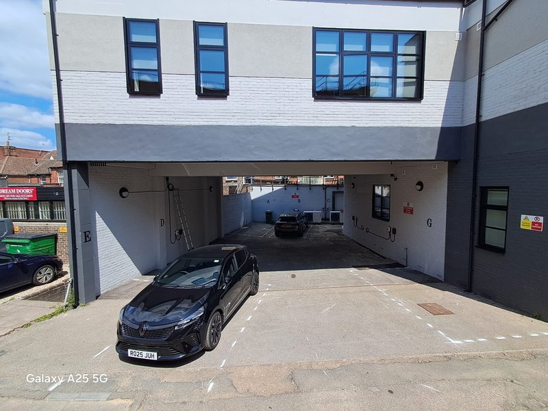 Modern residential building with covered parking area and black car parked underneath