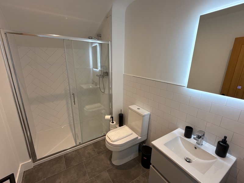 Modern bathroom with shower enclosure, toilet, sink and illuminated mirror