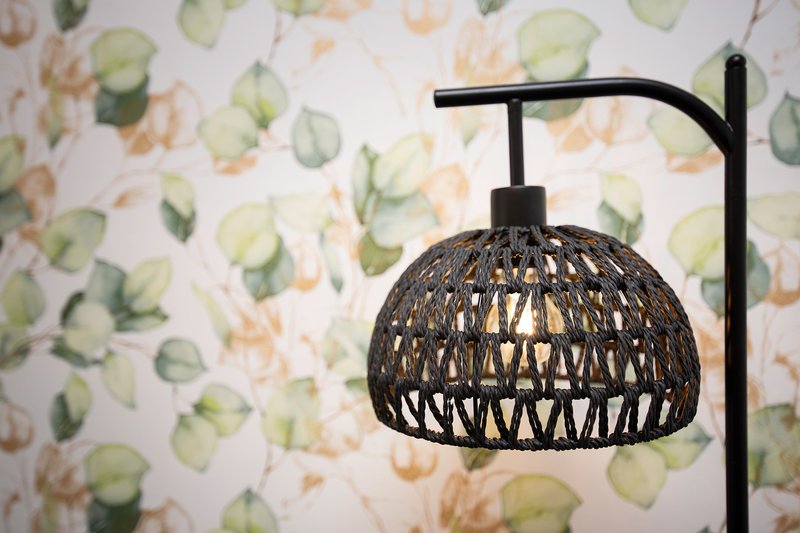 Black woven pendant lamp with floral wallpaper background in soft green and peach tones