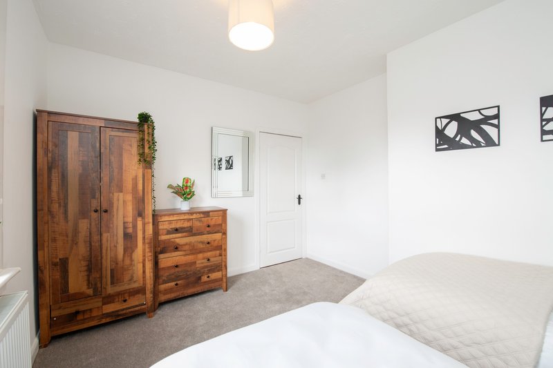Bedroom with wooden wardrobe, chest of drawers, single bed and ceiling light