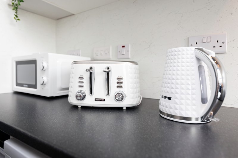 Kitchen counter with white microwave, toaster, and kettle appliances