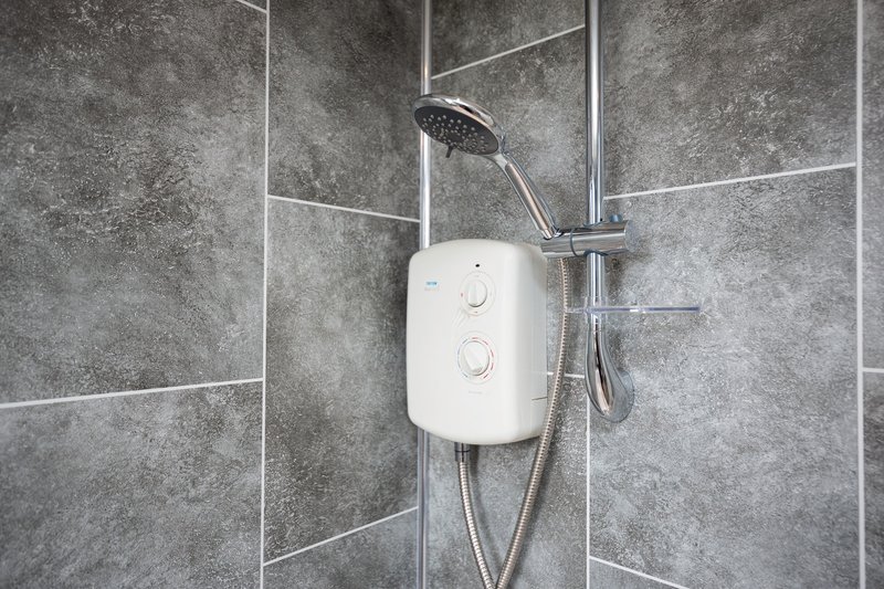 Modern bathroom shower with white electric heater unit and rainfall showerhead