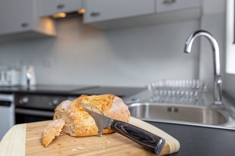 Modern kitchen with croissant on cutting board, sink and stainless steel faucet