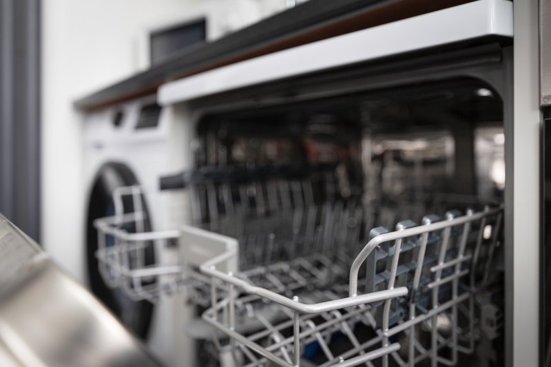 Open dishwasher with white racks, modern kitchen appliance detail