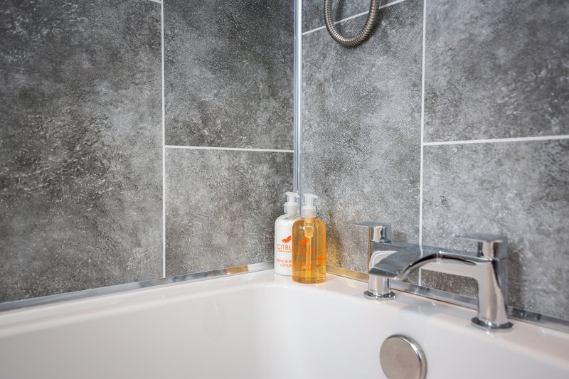Modern bathroom sink with chrome tap, soap dispenser, and grey tile splashback