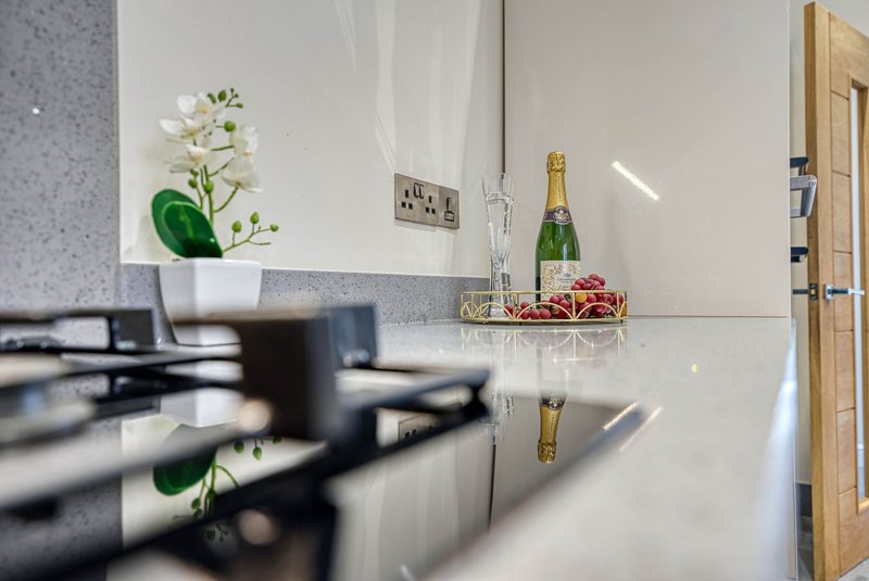 Modern kitchen countertop with white flowers, champagne bottle and decorative basket