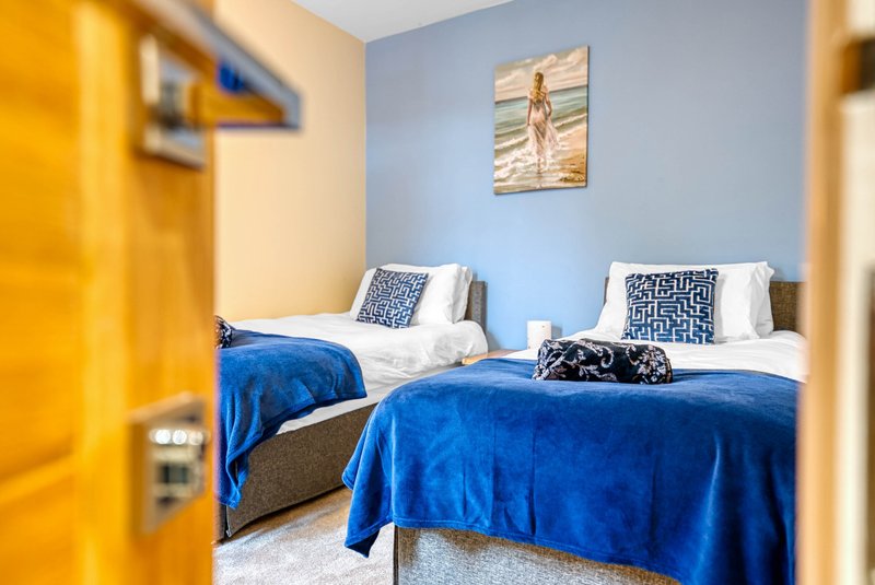 Twin bedroom with blue bedding, patterned pillows, and framed wall art.