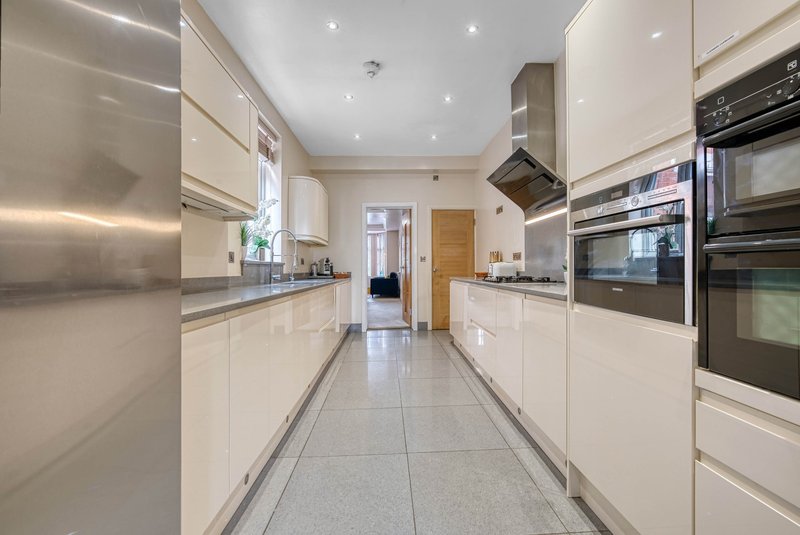 Modern galley kitchen with white cabinetry, stainless steel appliances and tiled flooring