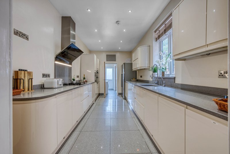 Modern galley kitchen with white cabinetry, stainless steel appliances, and grey tile flooring