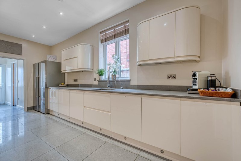 Modern kitchen with cream cabinetry, grey countertops, stainless steel appliances and tiled flooring