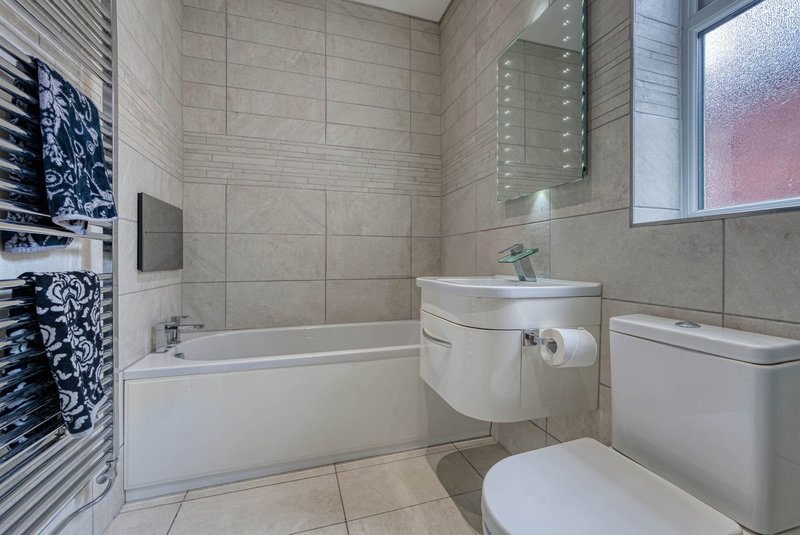 Modern bathroom with bathtub, toilet, sink, mirror and heated towel rail