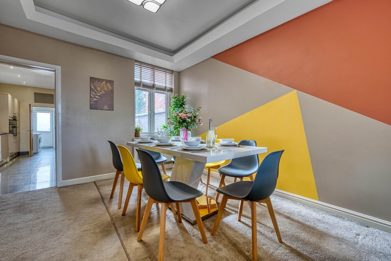 Modern dining area with geometric wall design, round table, and colorful chairs
